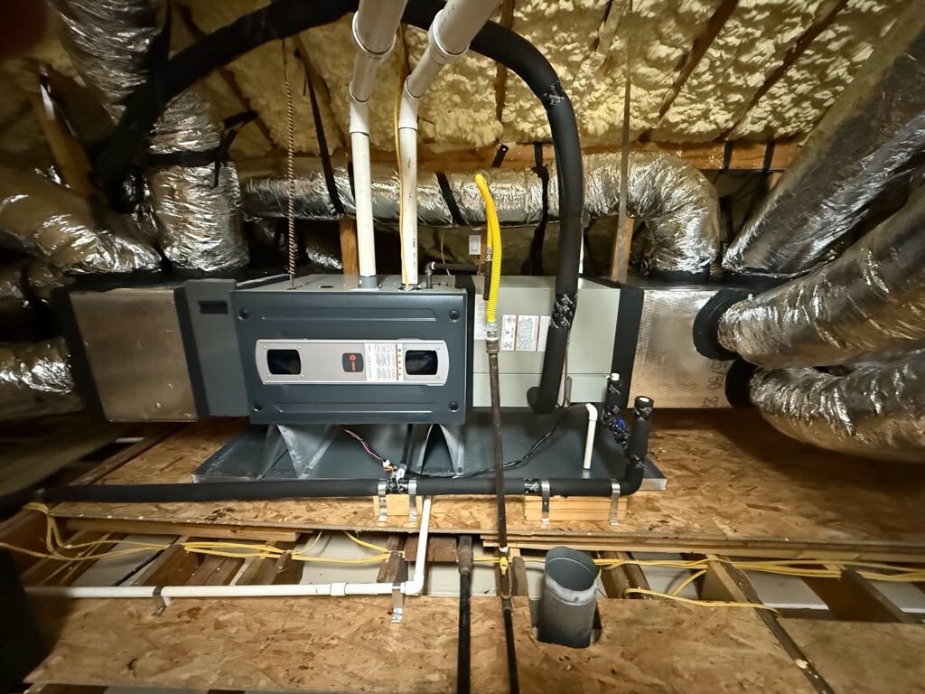 A Trane air handler in an attic under spray-foam insulation, with new drain lines and insulated ducts.